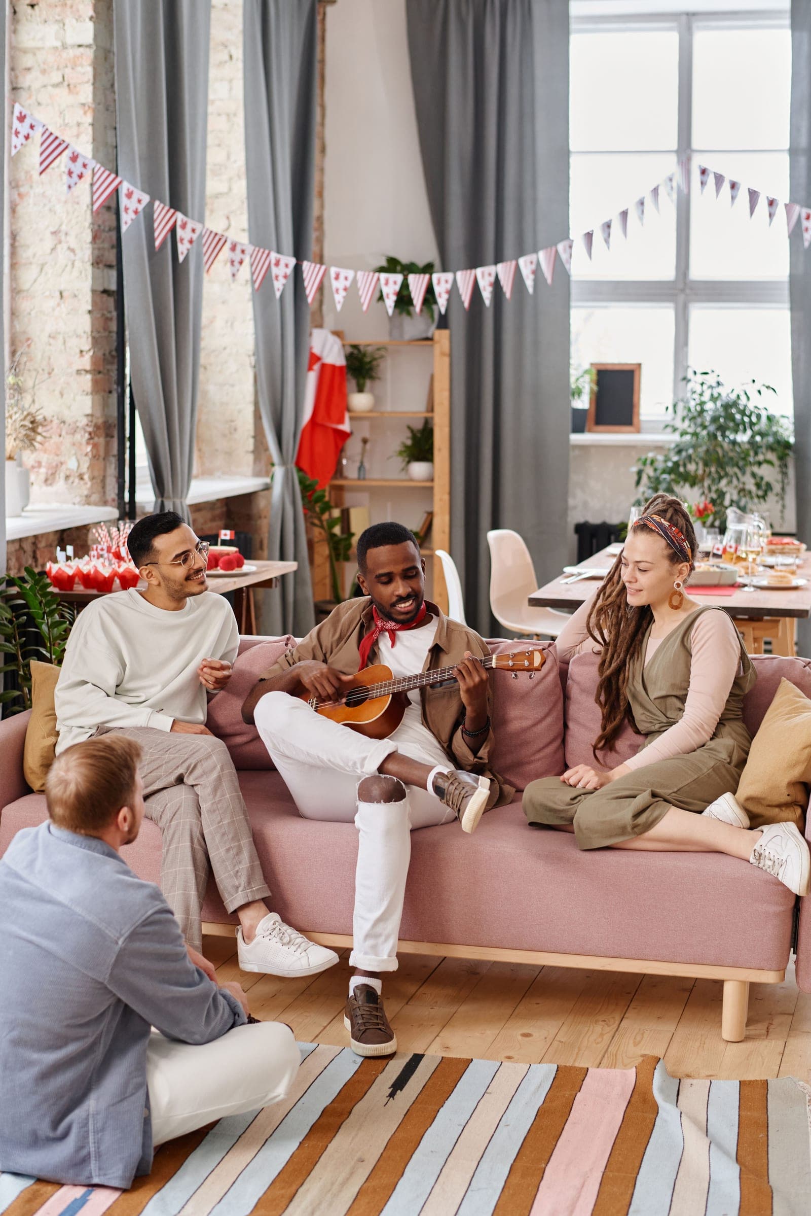 Friends together in a living room, one of them playing a ukulele