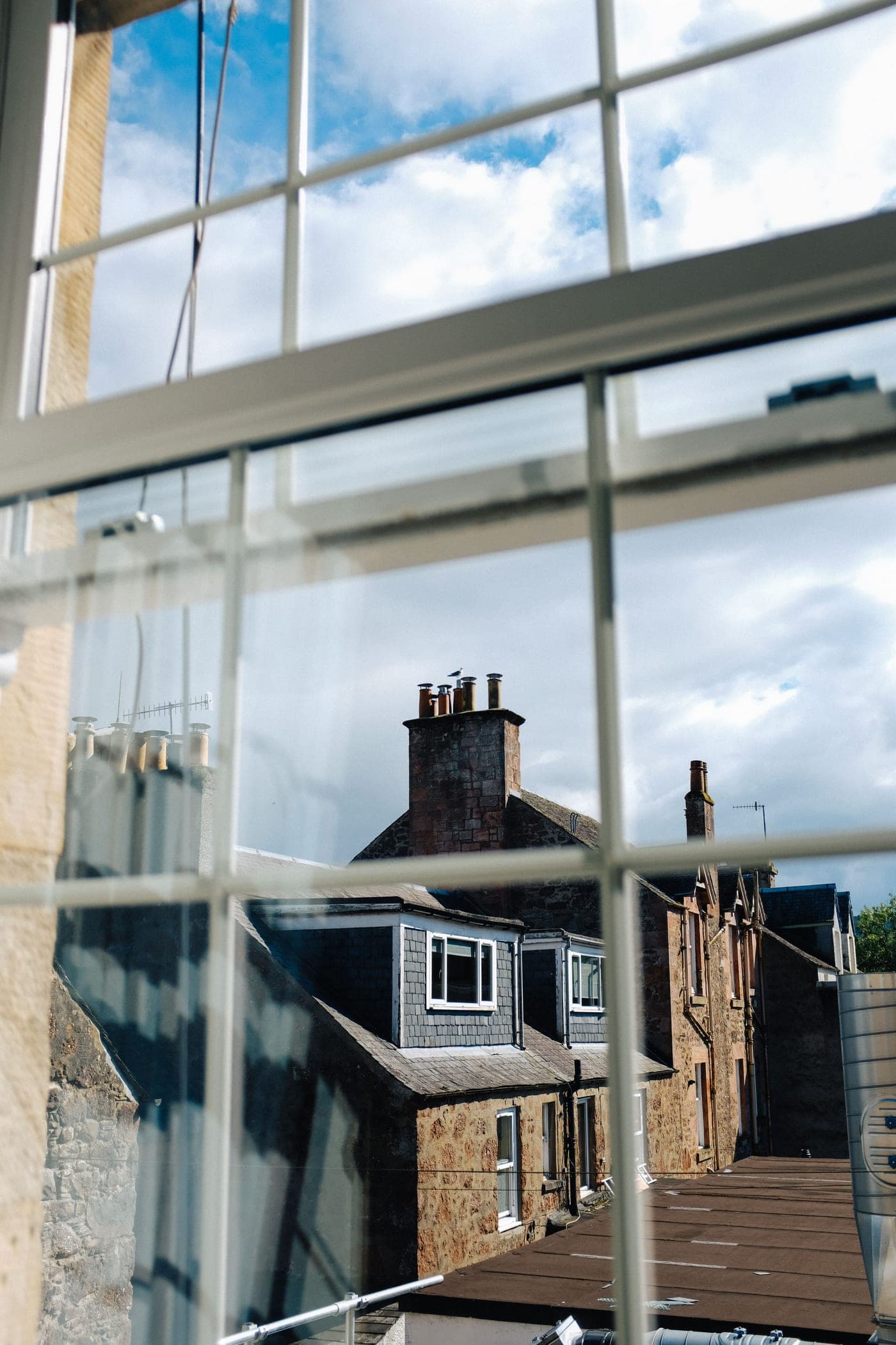 A row of stone houses and chimneys, seen through a window